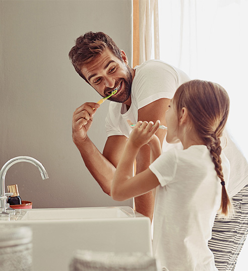 A dad brushing his teeth with his daughter